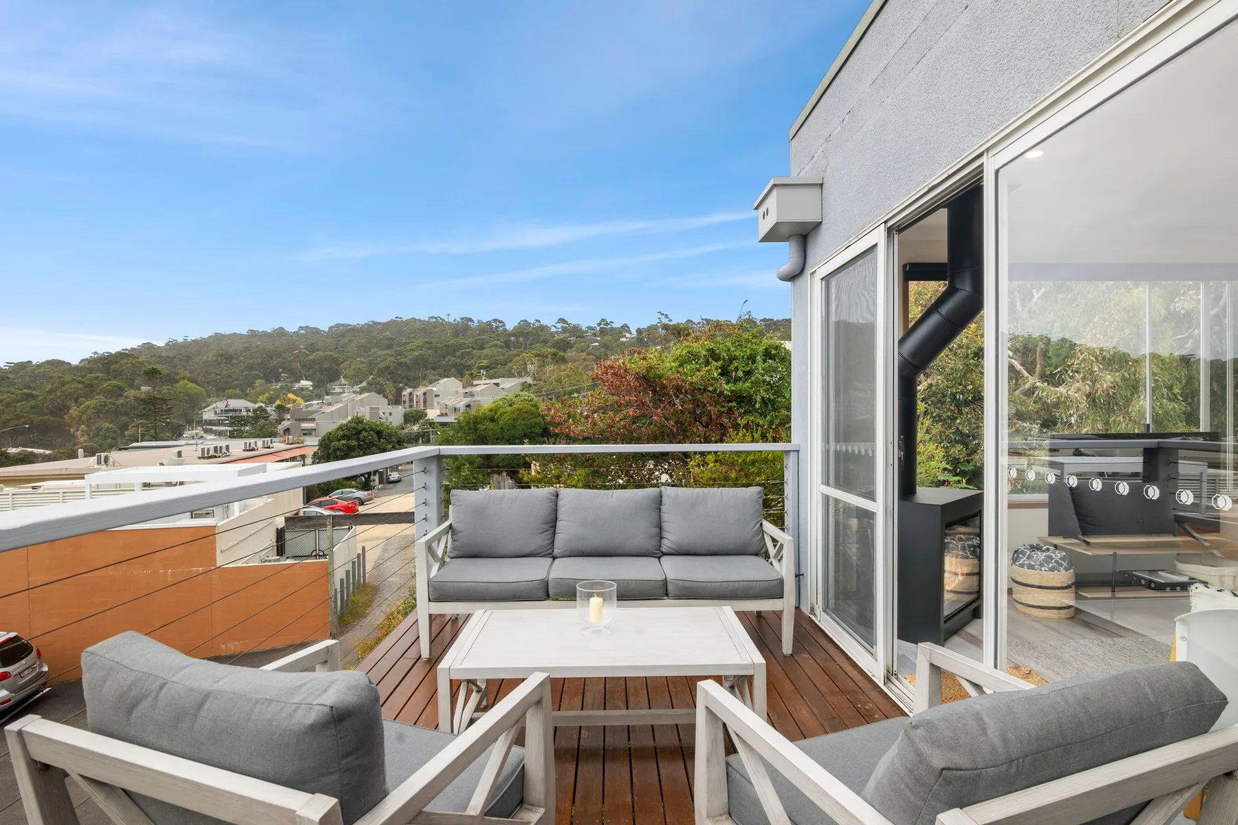 A rooftop patio has outdoor seating and a view of the surrounding hills.