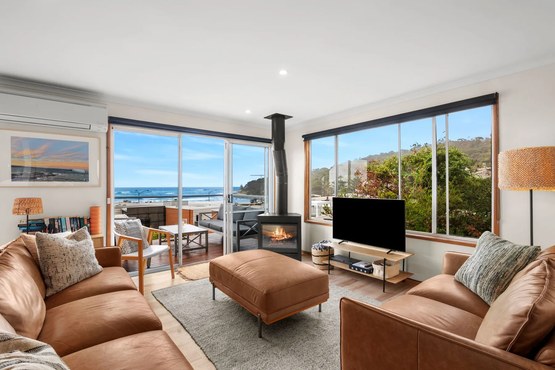 Living room with seating, a fireplace, and large windows overlooking the coast.