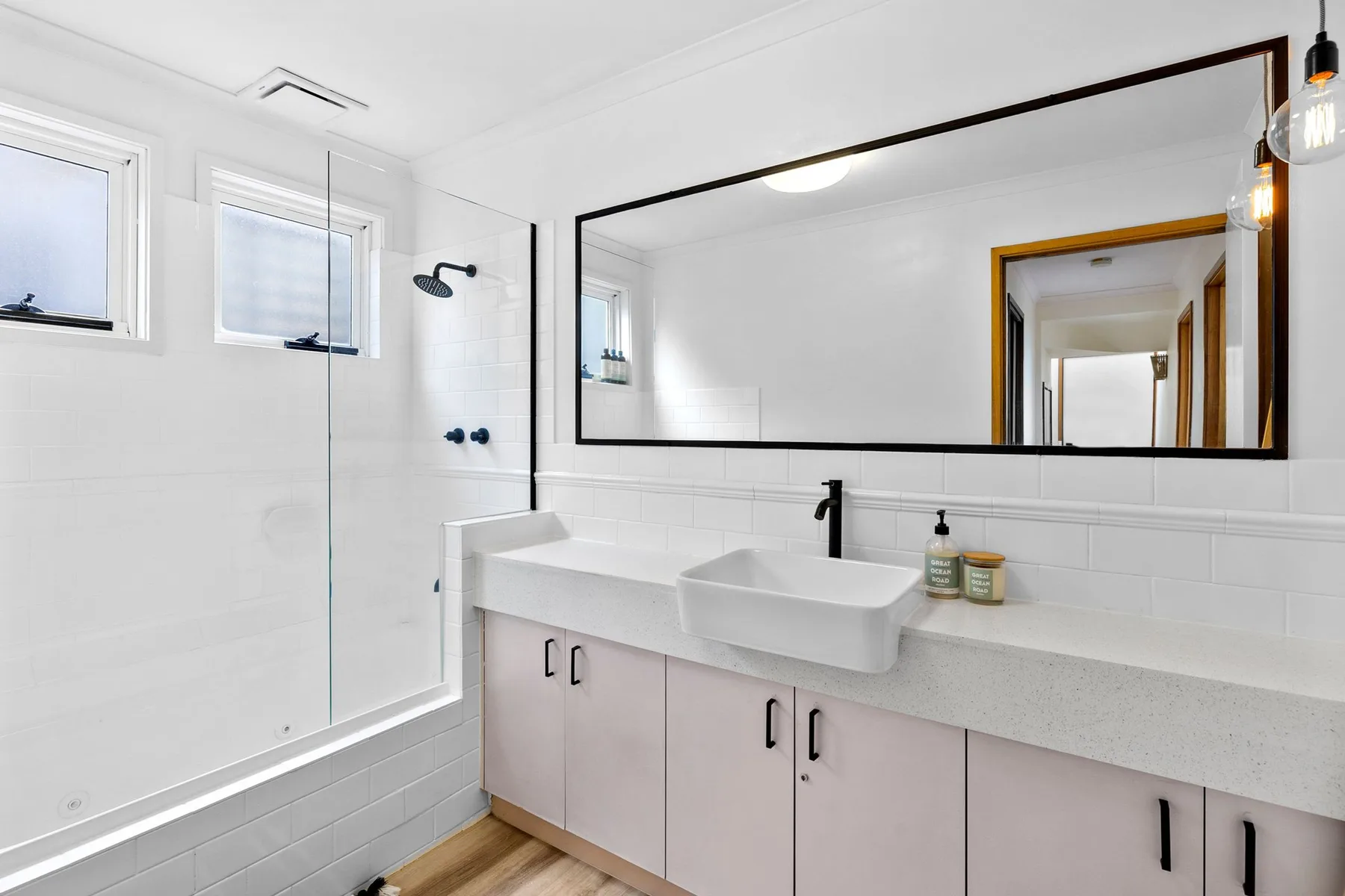 A bright bathroom with a wide mirror above the sink.