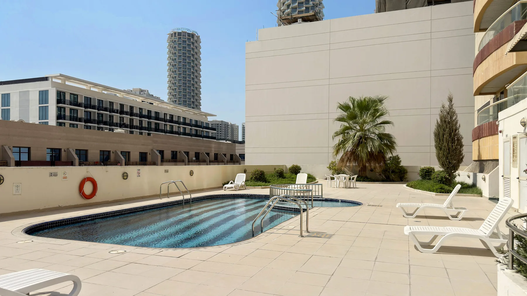 A rooftop pool area with lounge seating and surrounding city buildings.