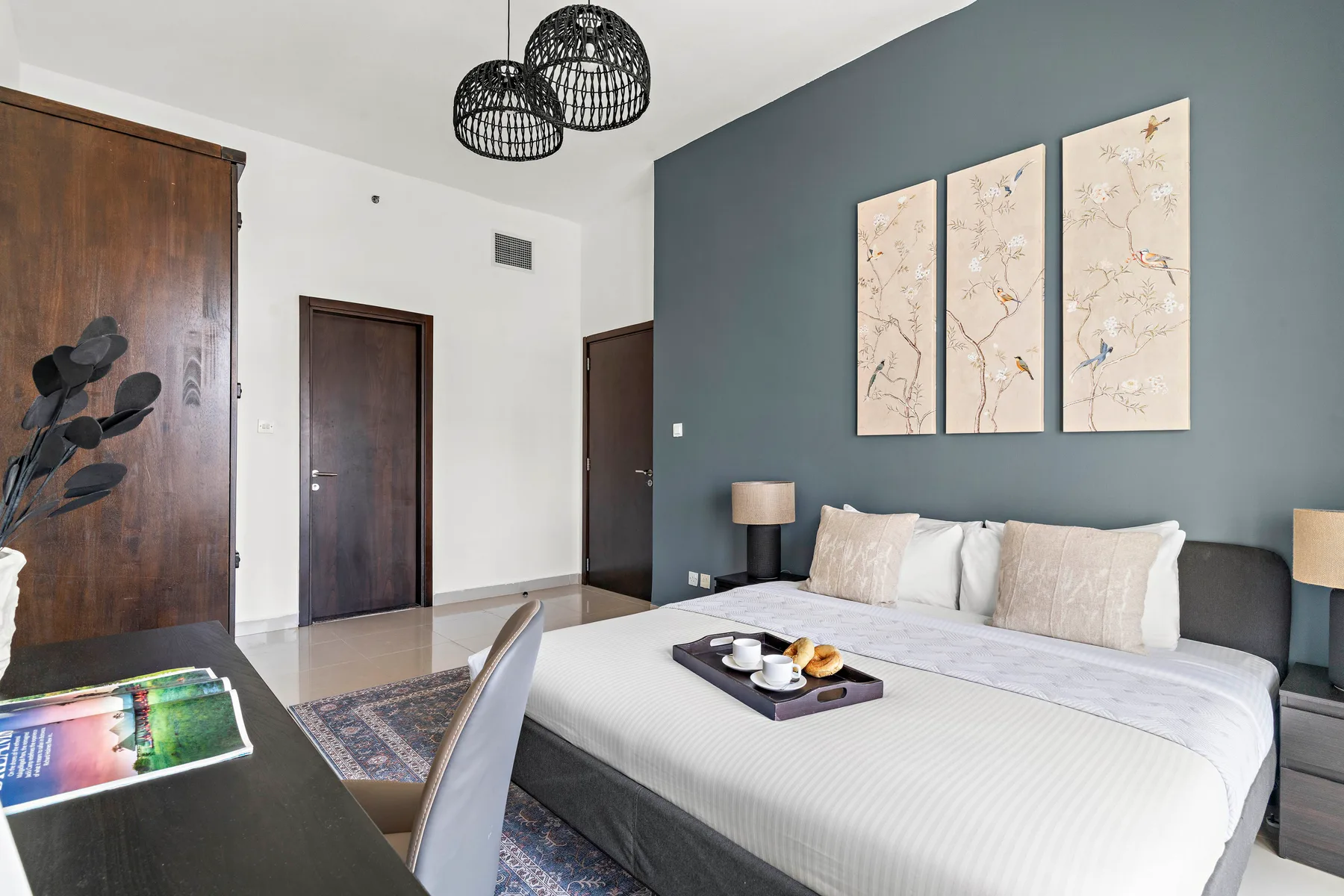 A bedroom with a neatly made bed, wall art, and a dark accent wall.