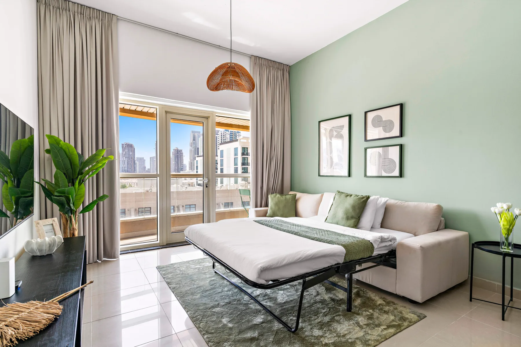 Una sala luminosa con sofá seccional, mesa de centro y ventanas con vista a edificios de la ciudad.