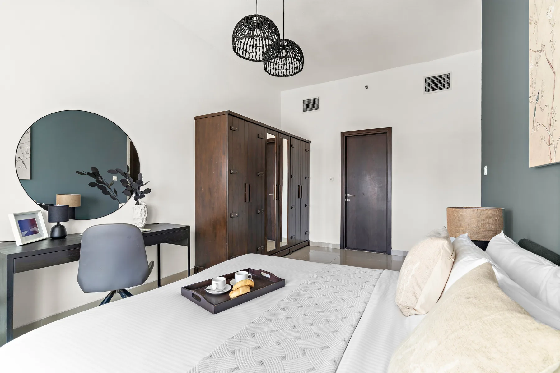 A bedroom with a bed, desk, and wardrobe.