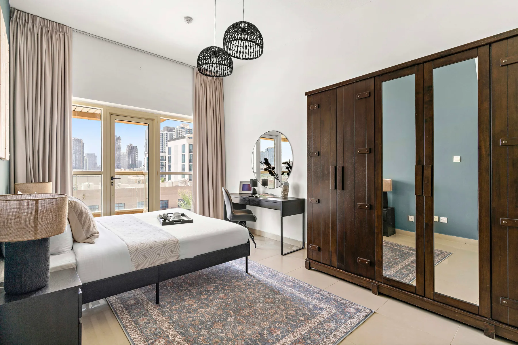 A bedroom with a bed, a desk, and a large mirrored wardrobe.