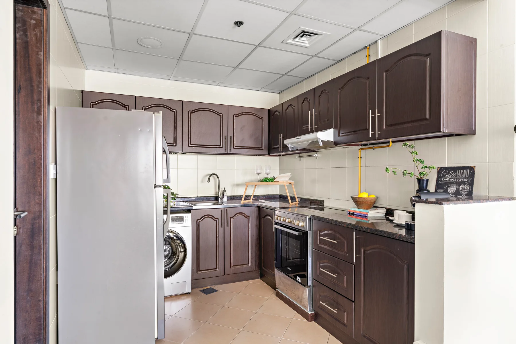 A compact kitchen with dark cabinets, a refrigerator, and a stove.