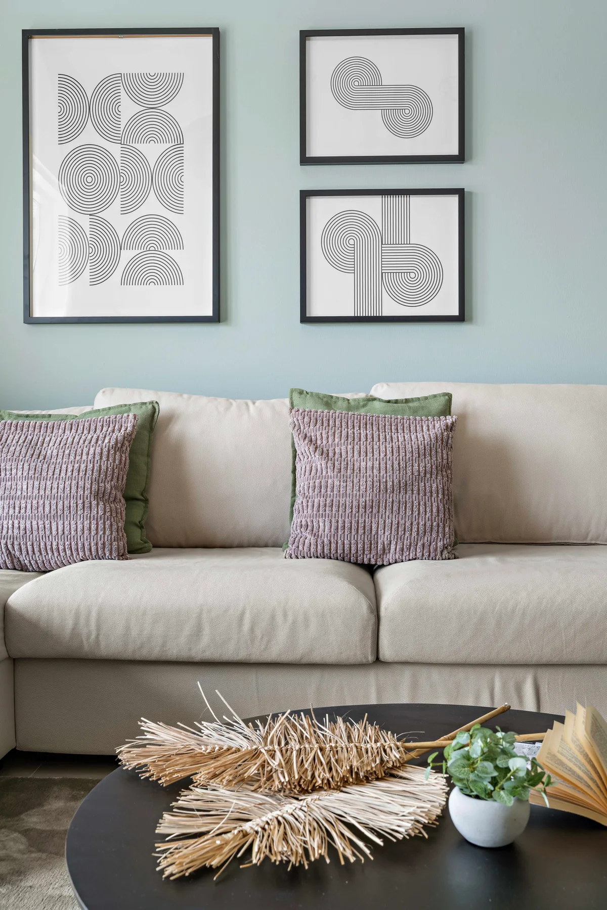 A living room with a light sofa beneath three framed geometric prints.