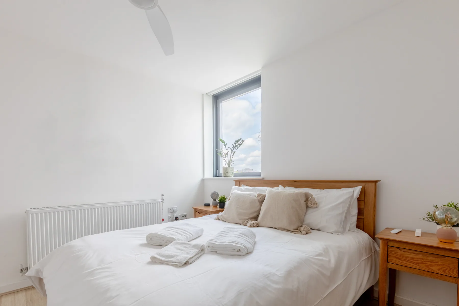 Un dormitorio luminoso con una cama, ropa de cama blanca y una ventana.