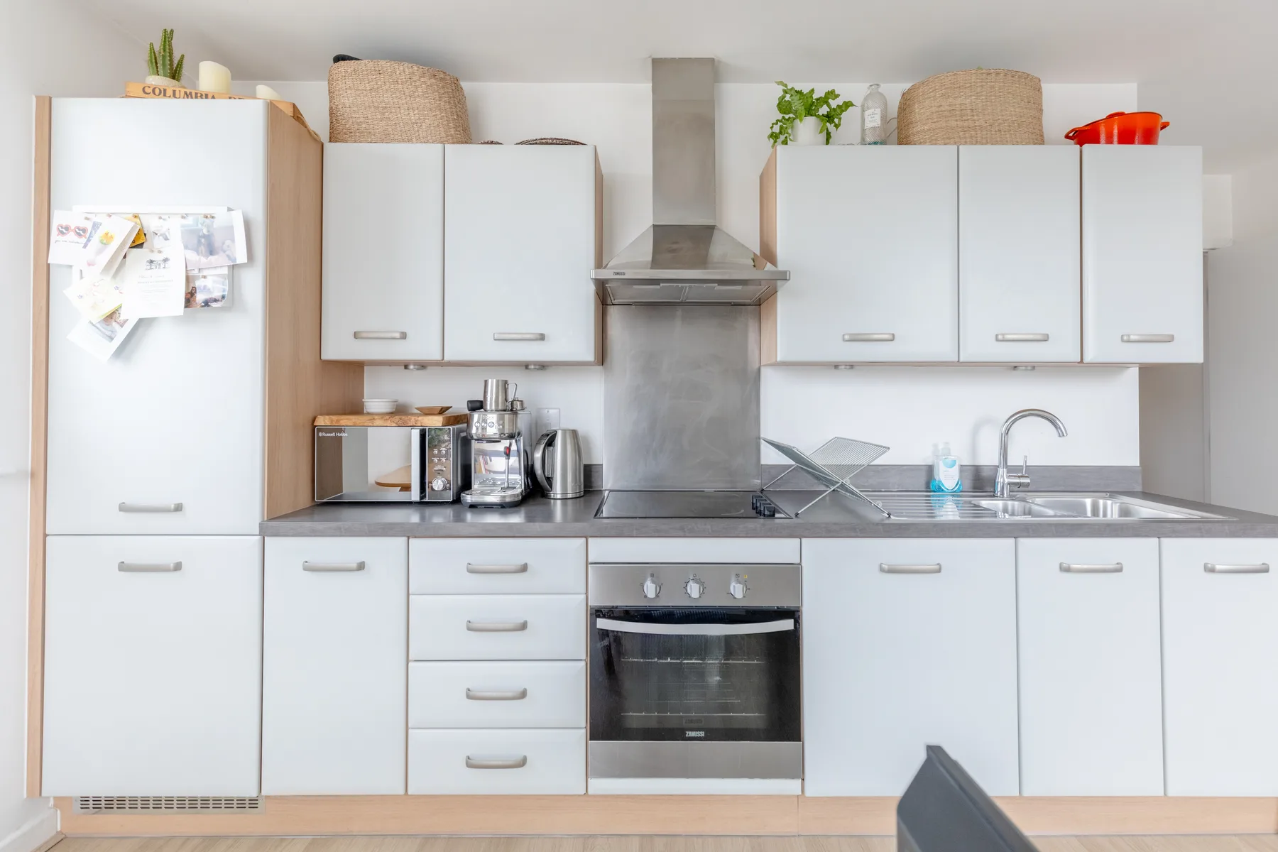 Una cocina luminosa con gabinetes blancos, una encimera y un horno integrado.
