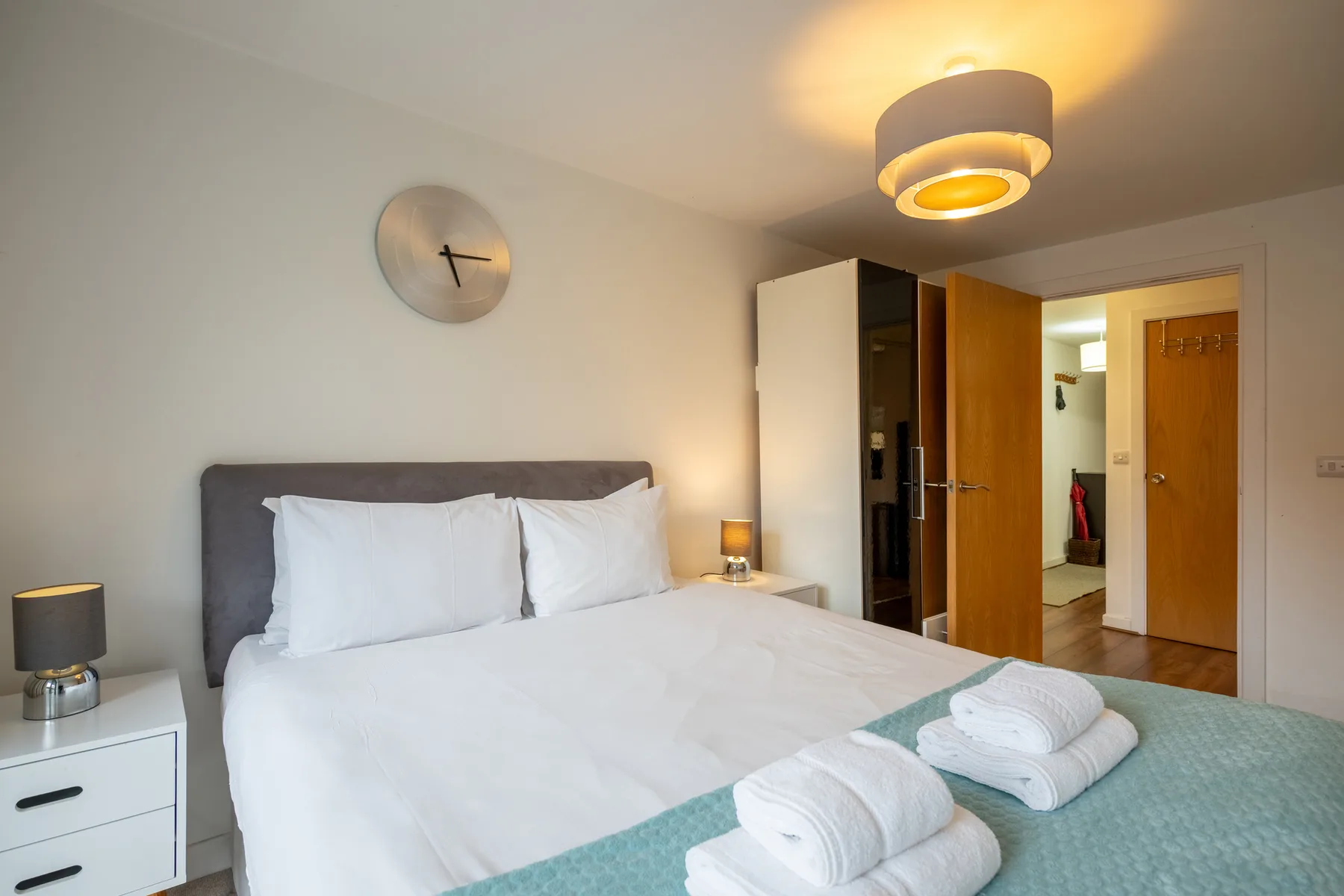 A bedroom with a neatly made bed and an open doorway.
