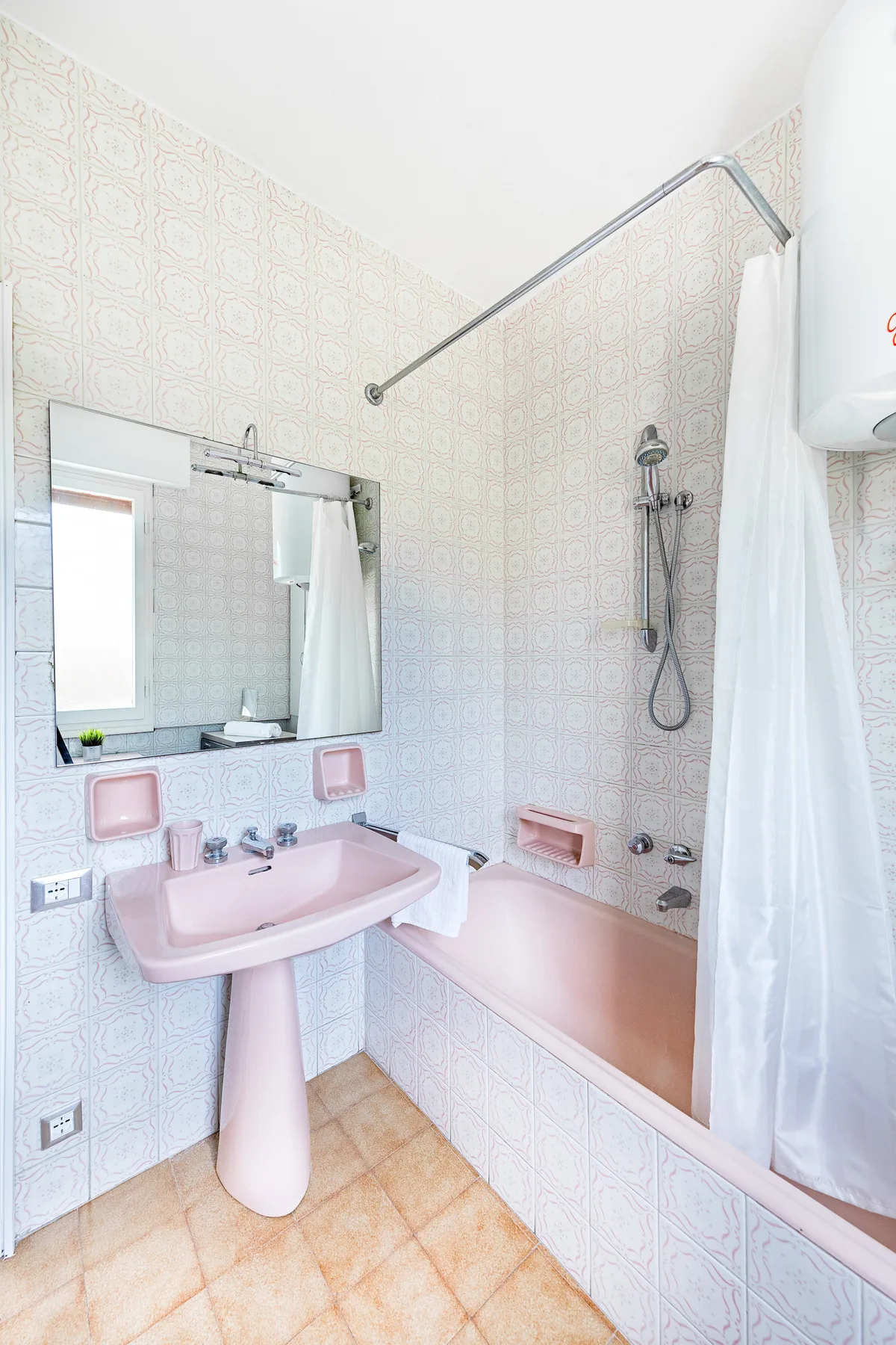 Un baño alicatado con lavabo rosa, bañera y ducha.