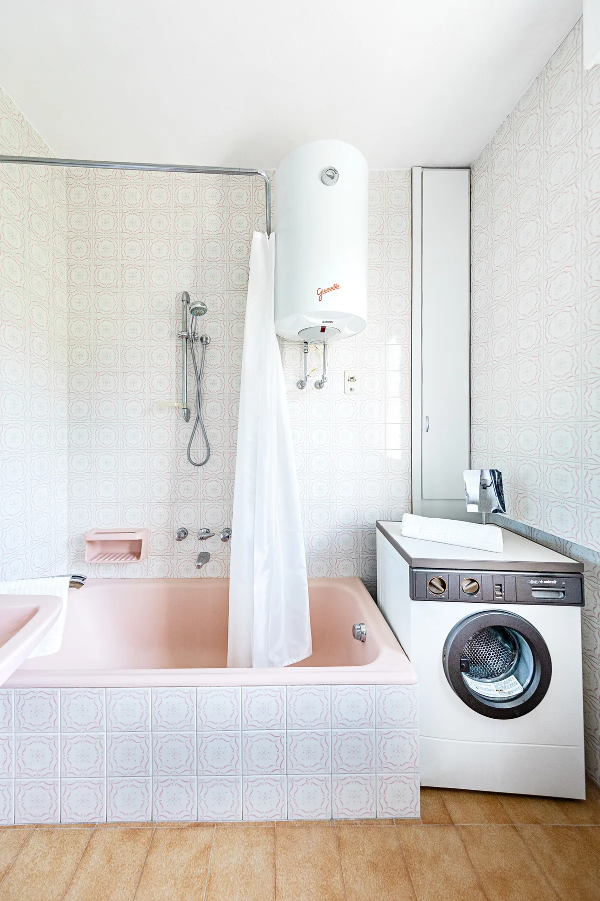 Un baño alicatado con bañera, ducha de pared y lavadora.