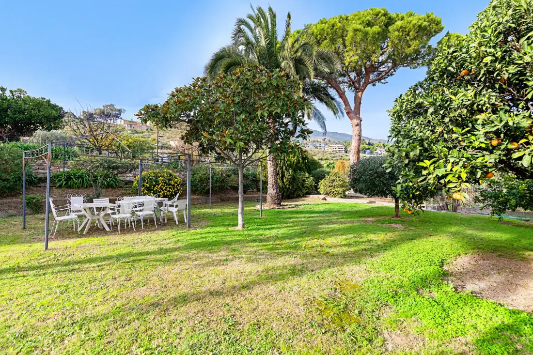 Un jardín ajardinado con césped, árboles y asientos al aire libre.