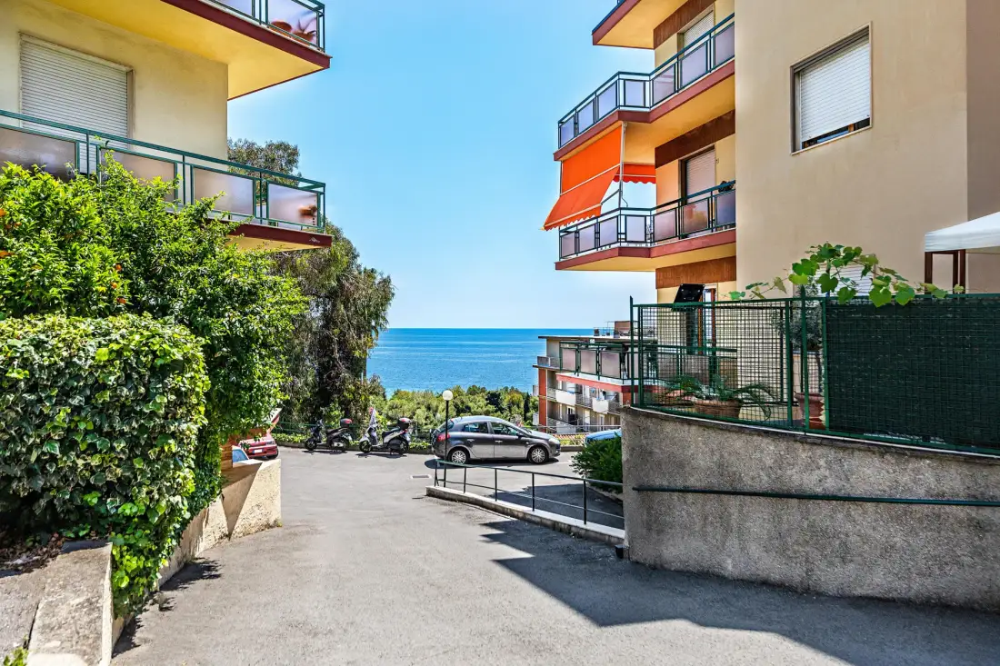 Un camino pavimentado pasa entre edificios de apartamentos y conduce hacia el mar.