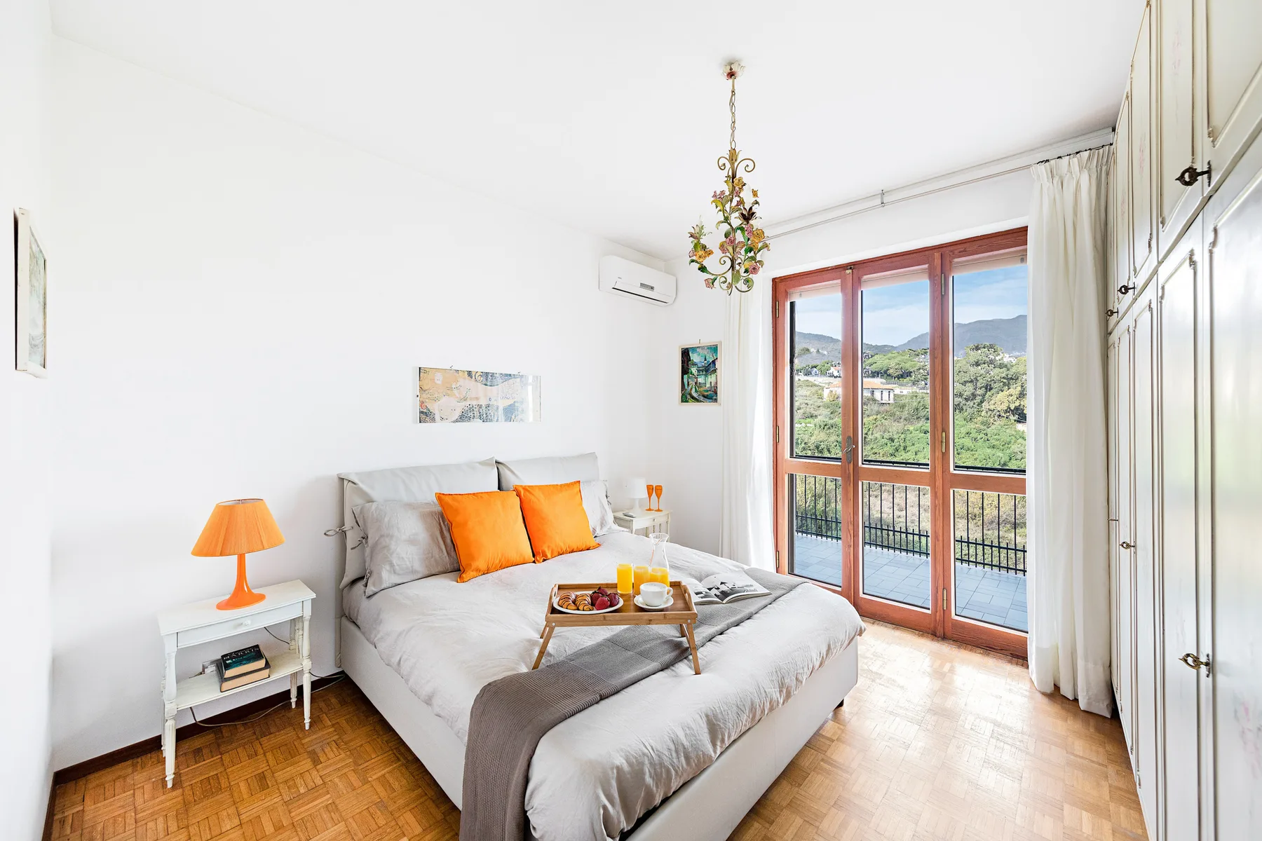 A bright bedroom with a double bed and glass doors opening onto a balcony.