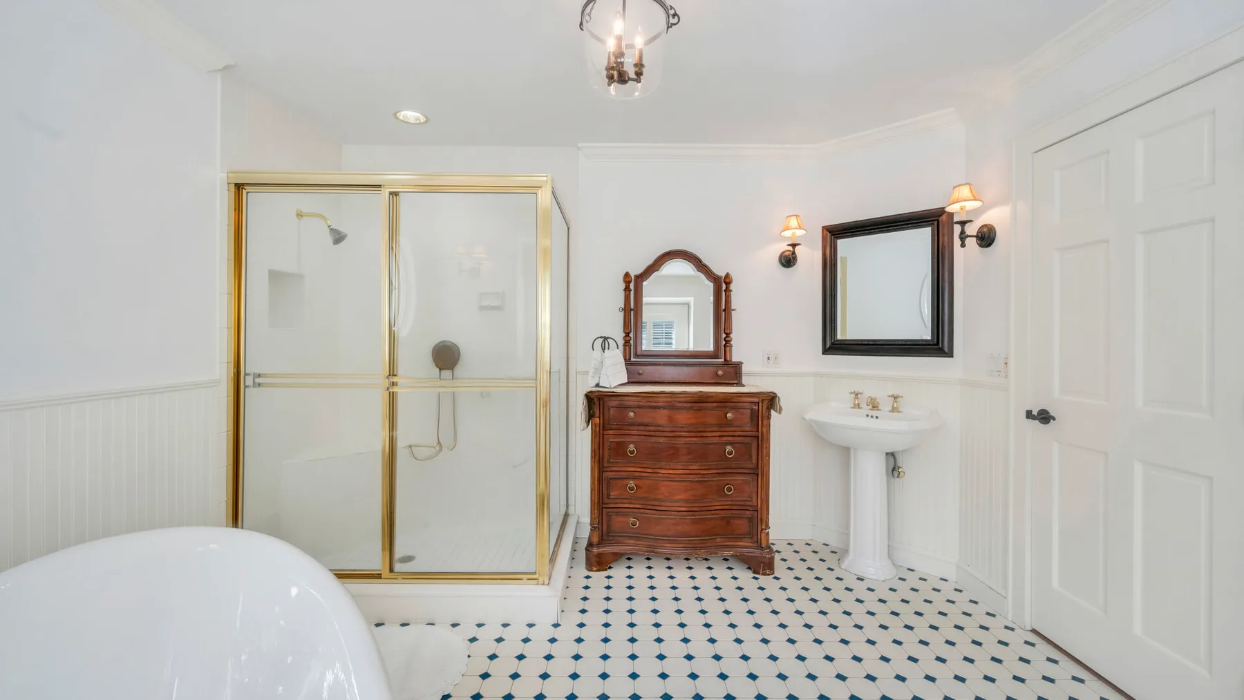 Un baño luminoso con ducha de vidrio, tocador y lavabo de pedestal.