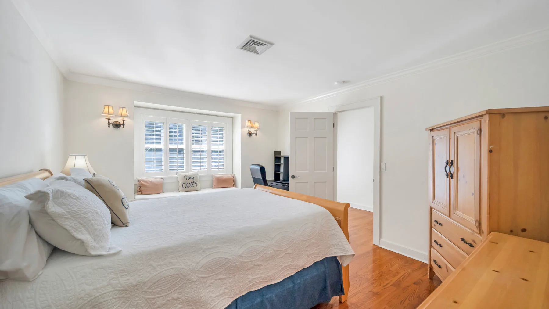 Un dormitorio luminoso con una cama grande, una ventana y muebles de madera.