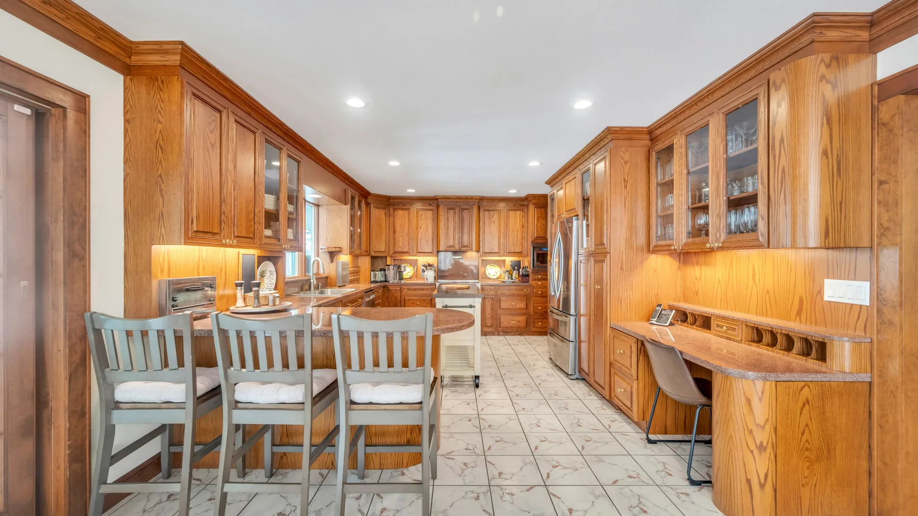 Una cocina amplia con gabinetes de madera, una isla central y una barra para desayunar.