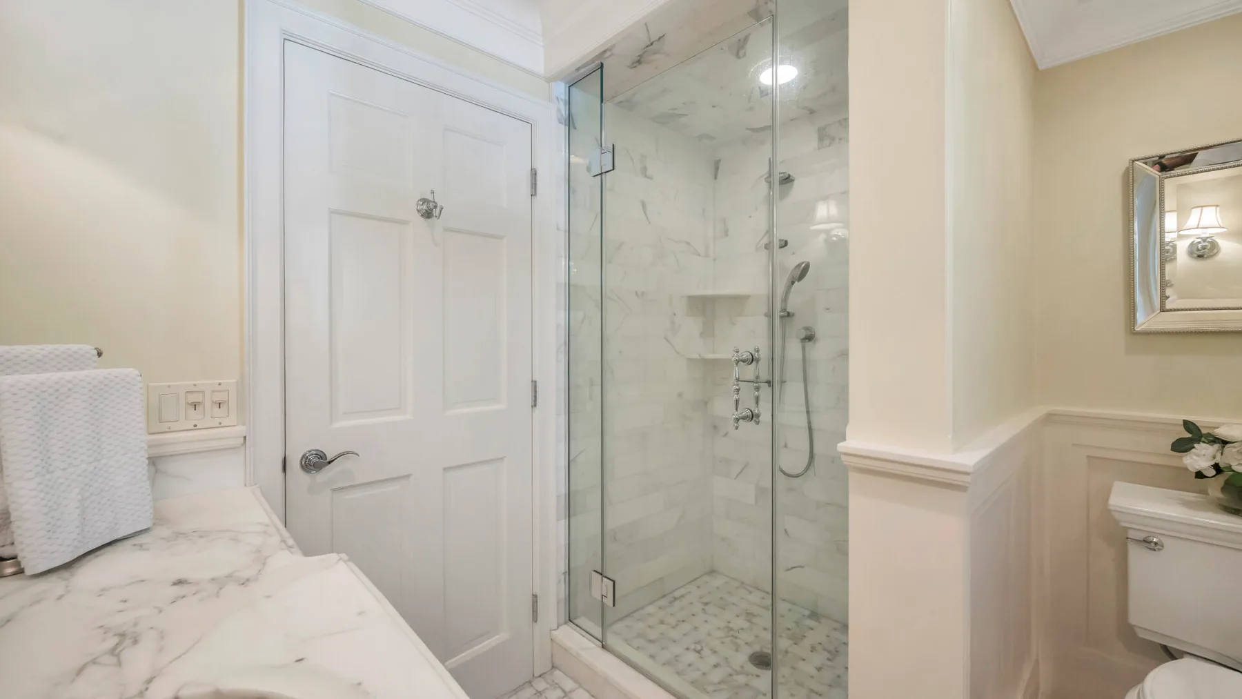 Un baño con una ducha de vidrio y una encimera de mármol.