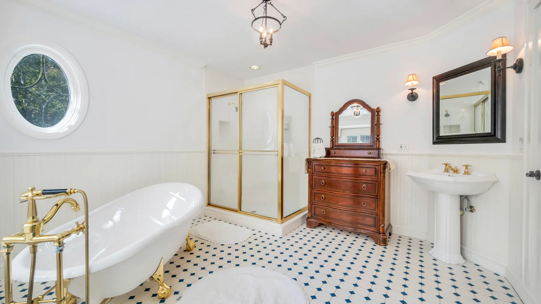 Un baño luminoso cuenta con una bañera exenta, una ducha acristalada y un lavabo con pedestal.