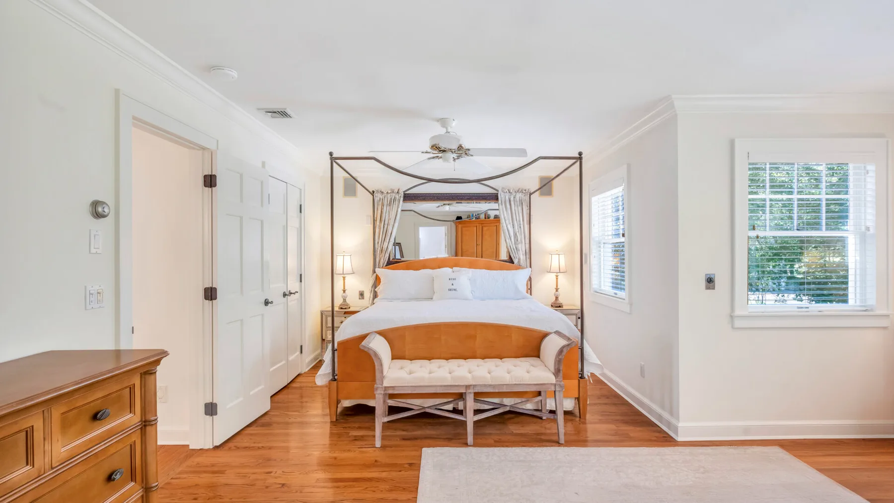 Un dormitorio luminoso cuenta con una cama con dosel y suelo de madera cálida.