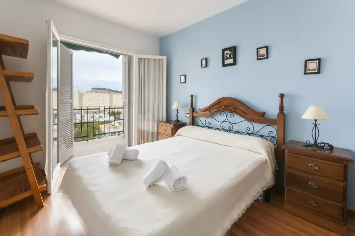 A bedroom with a bed and an open doorway leading to a balcony.