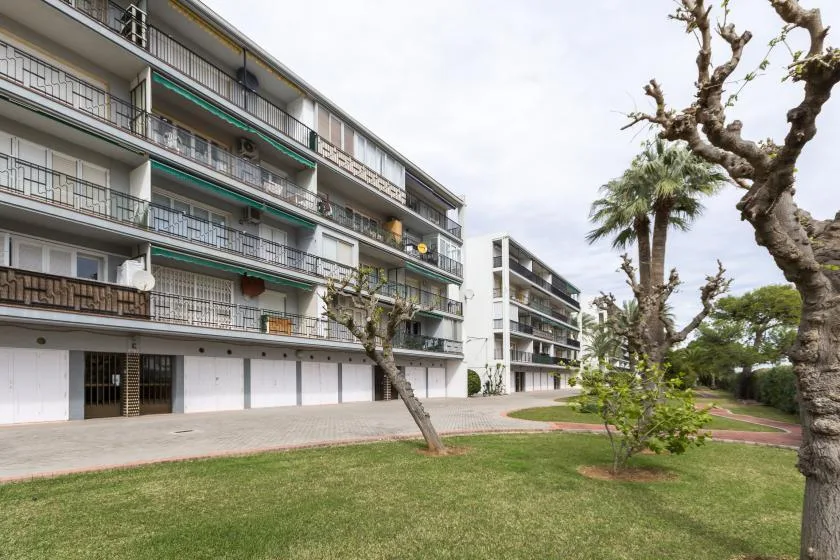 Apartment buildings stand beside a grassy courtyard with trees.