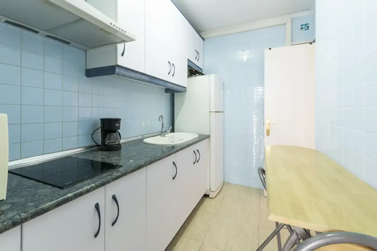 A tiled kitchen with a countertop, cooktop, and dining table.