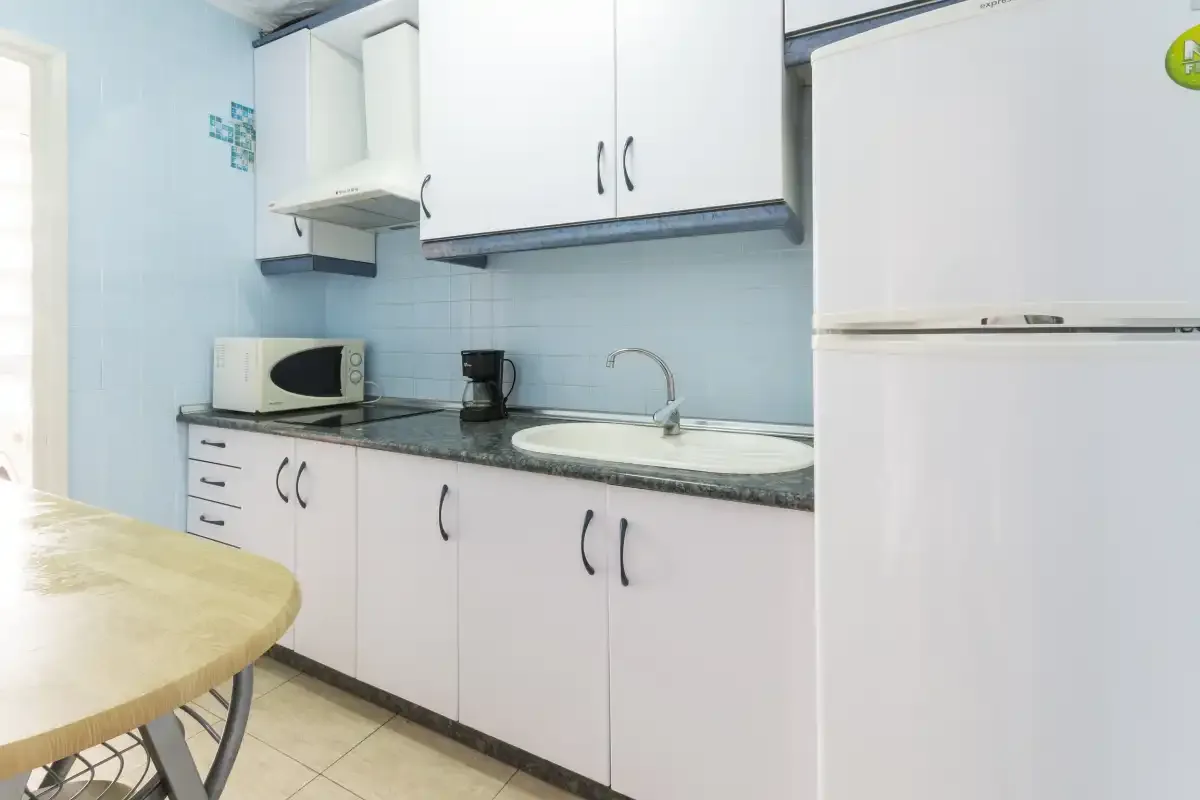 A compact kitchen with white cabinets, a countertop, and a sink.