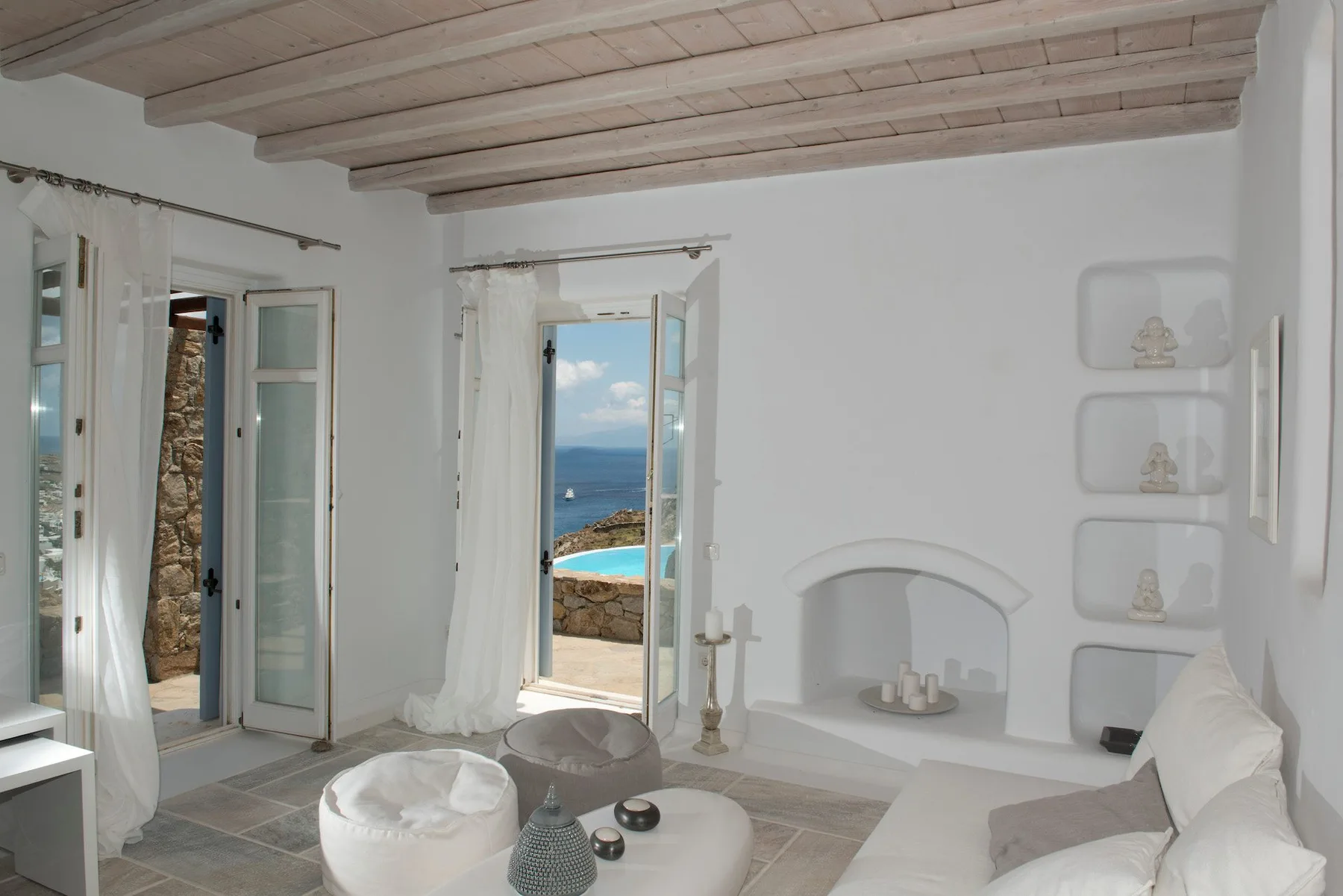 A bright white living room opens onto a view of the sea.