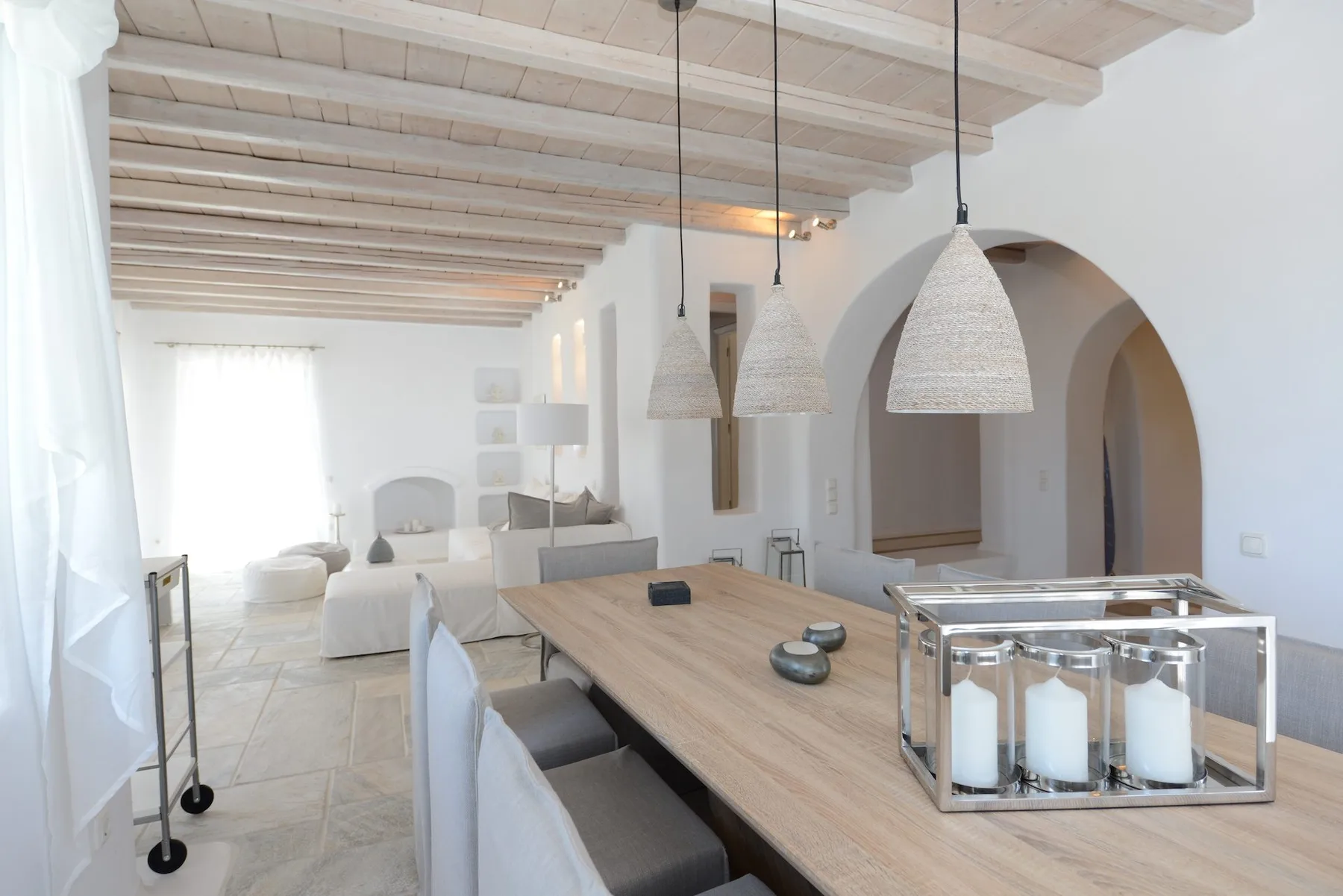 A bright dining area with a long wooden table and woven pendant lights.
