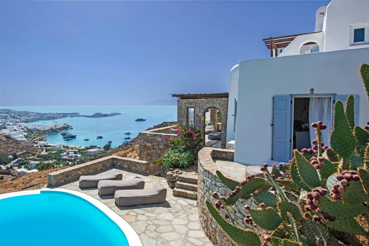 A seaside villa patio with a swimming pool and a view of the bay.