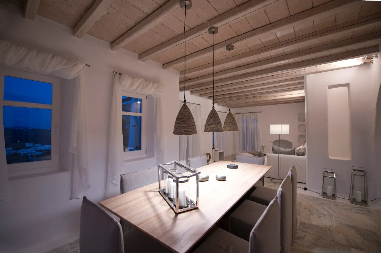 A dining area with a long table beneath three woven pendant lights.