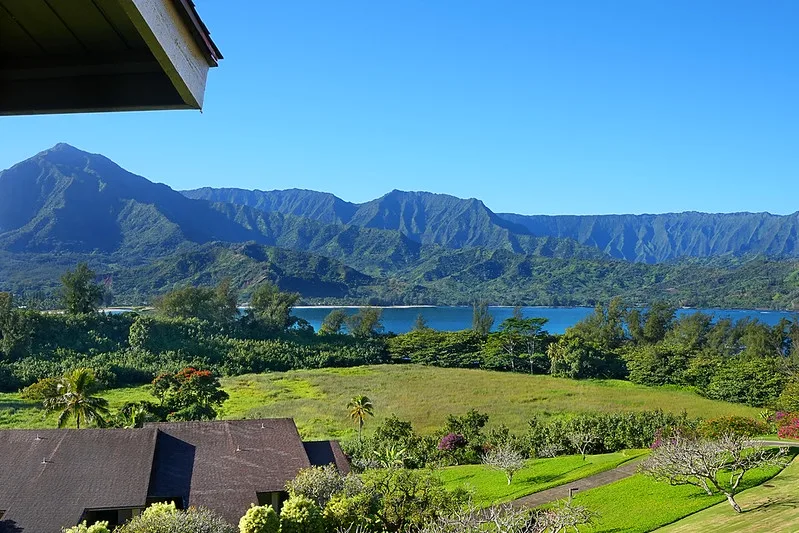 A mountain and lake landscape overlooks green gardens and rooftops.