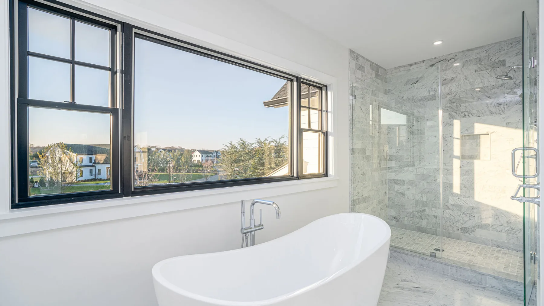 A bright bathroom features a freestanding tub beside a glass shower.
