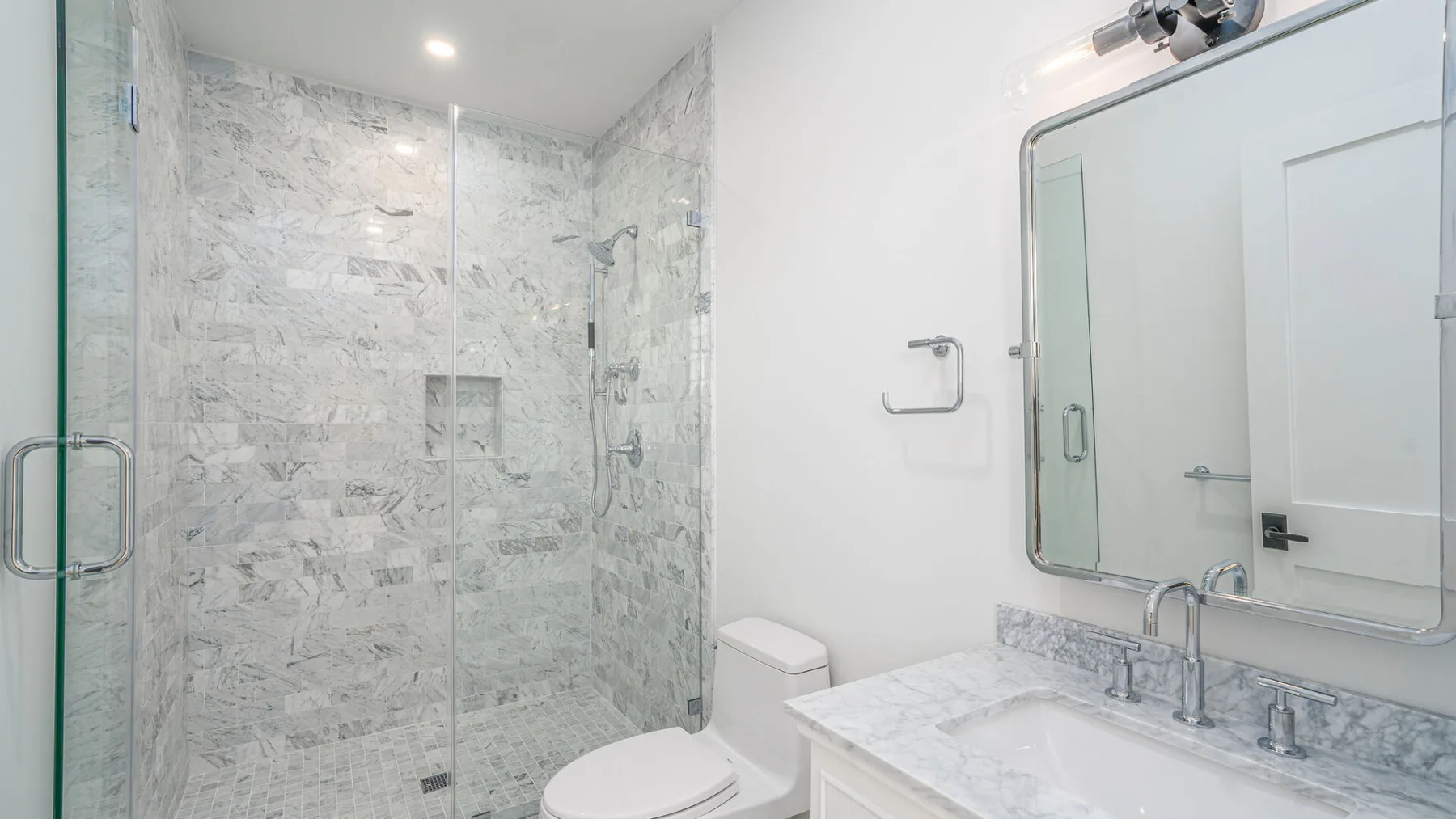 A bright bathroom with a glass-enclosed shower and a sink.