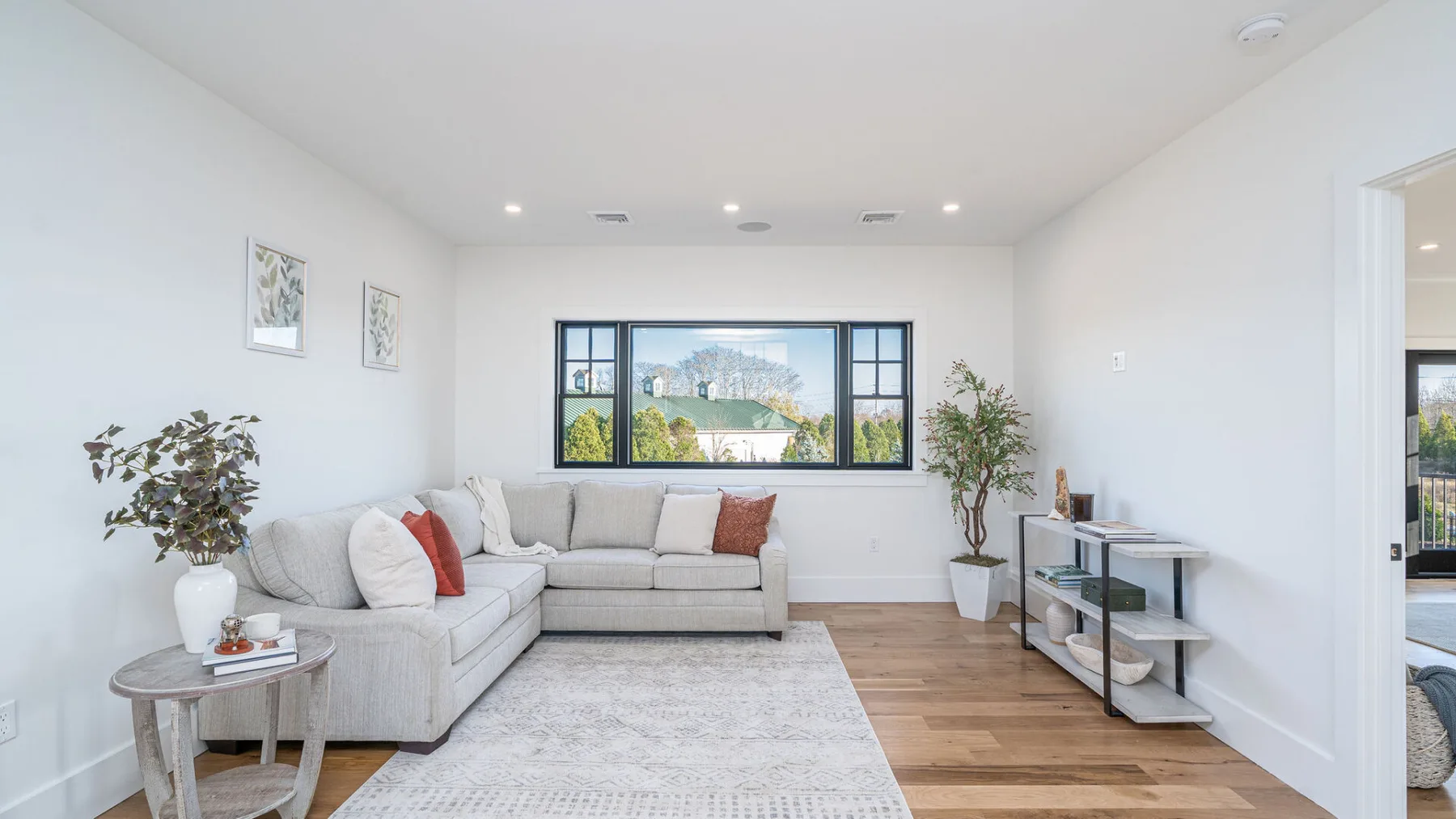 A bright living room with a sectional seating area, rug, and wide windows.