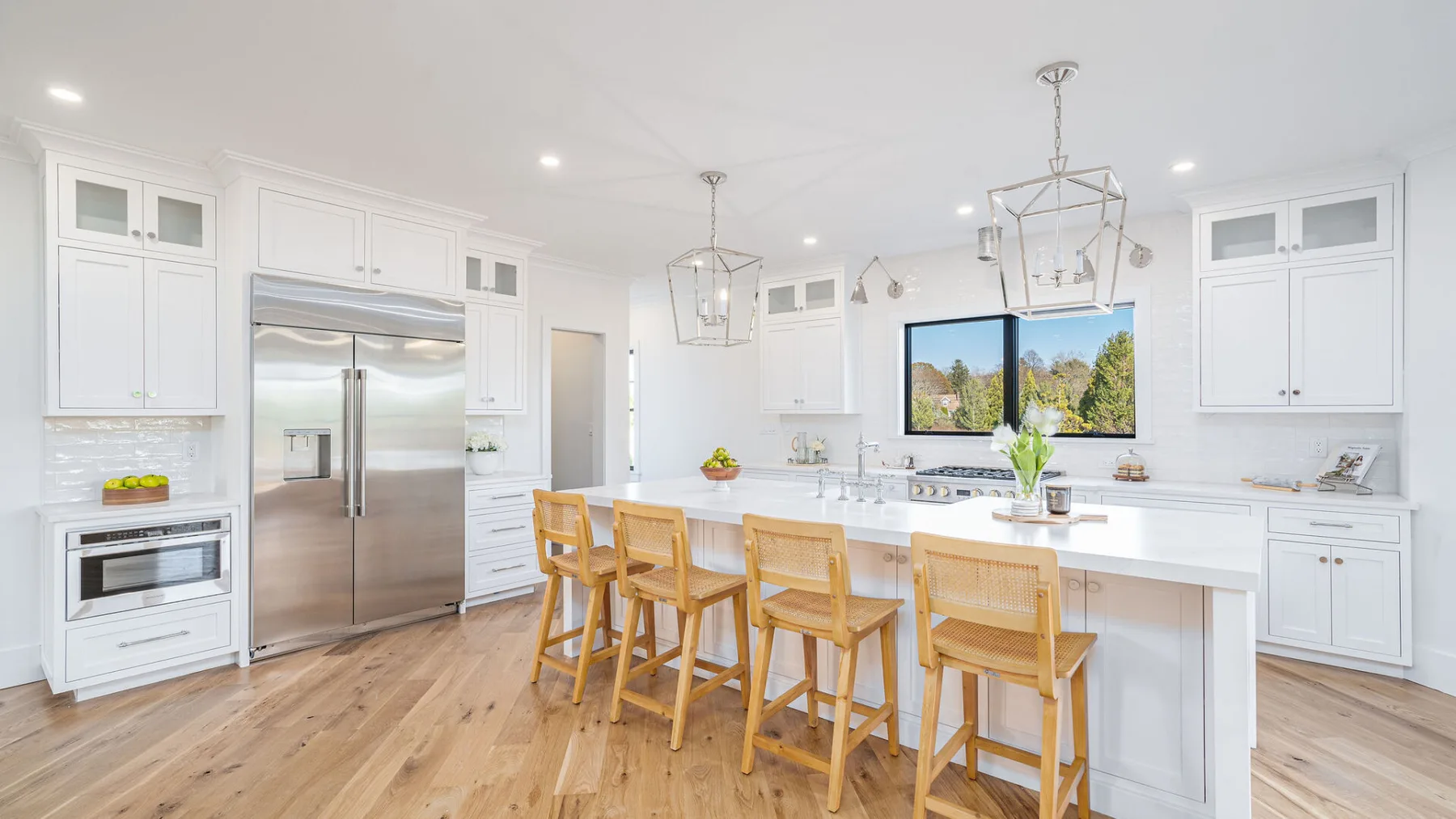 A bright kitchen with white cabinetry, a central island, and wooden seating.