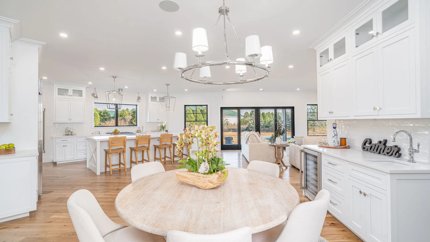 A bright kitchen and dining area with a large round table and white cabinetry.
