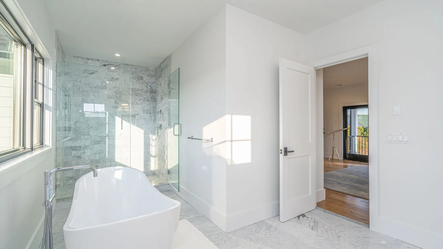 A bright bathroom with a freestanding bathtub and glass shower.