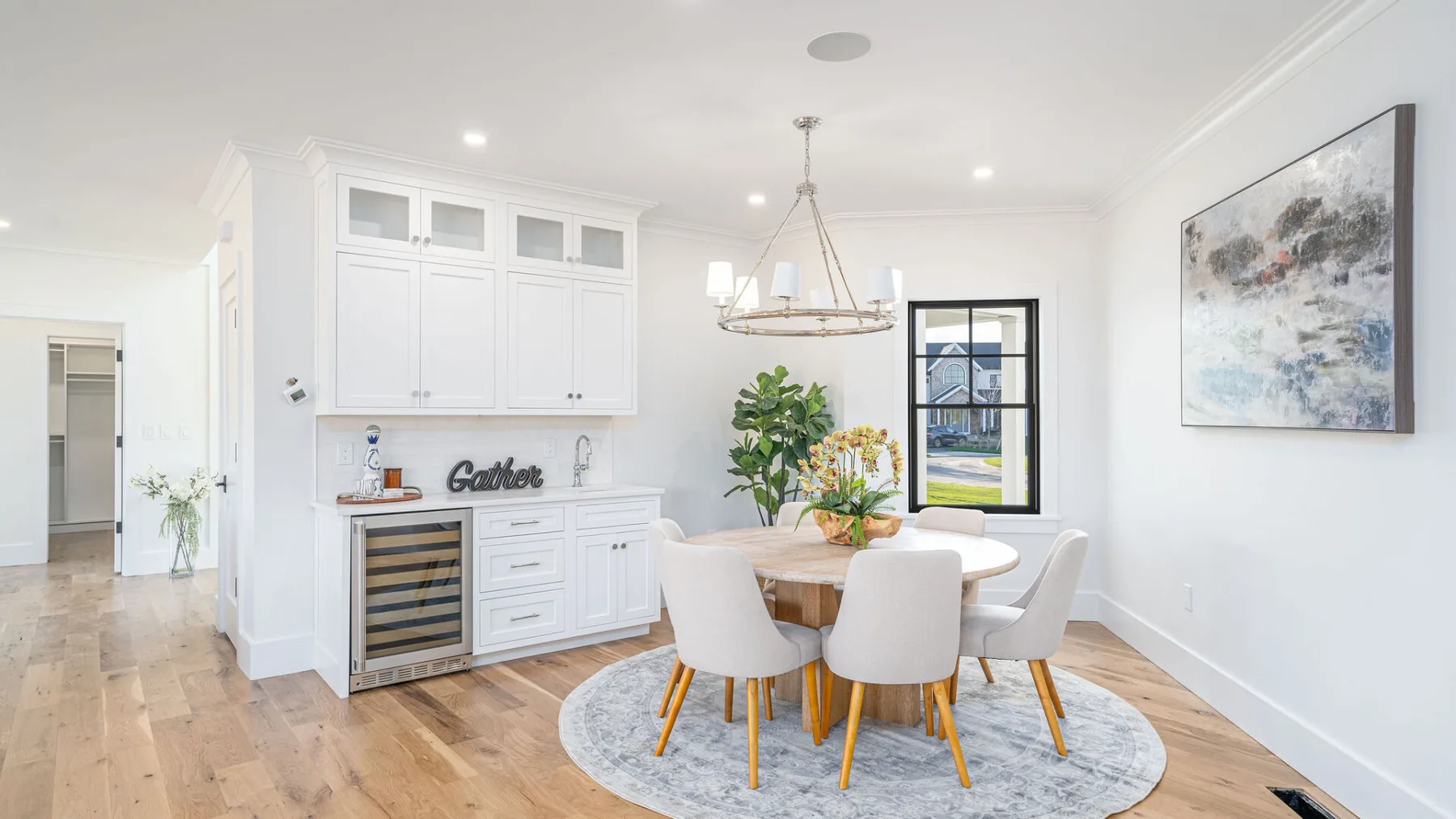 A bright dining room with a round table, upholstered seating, and white cabinetry.