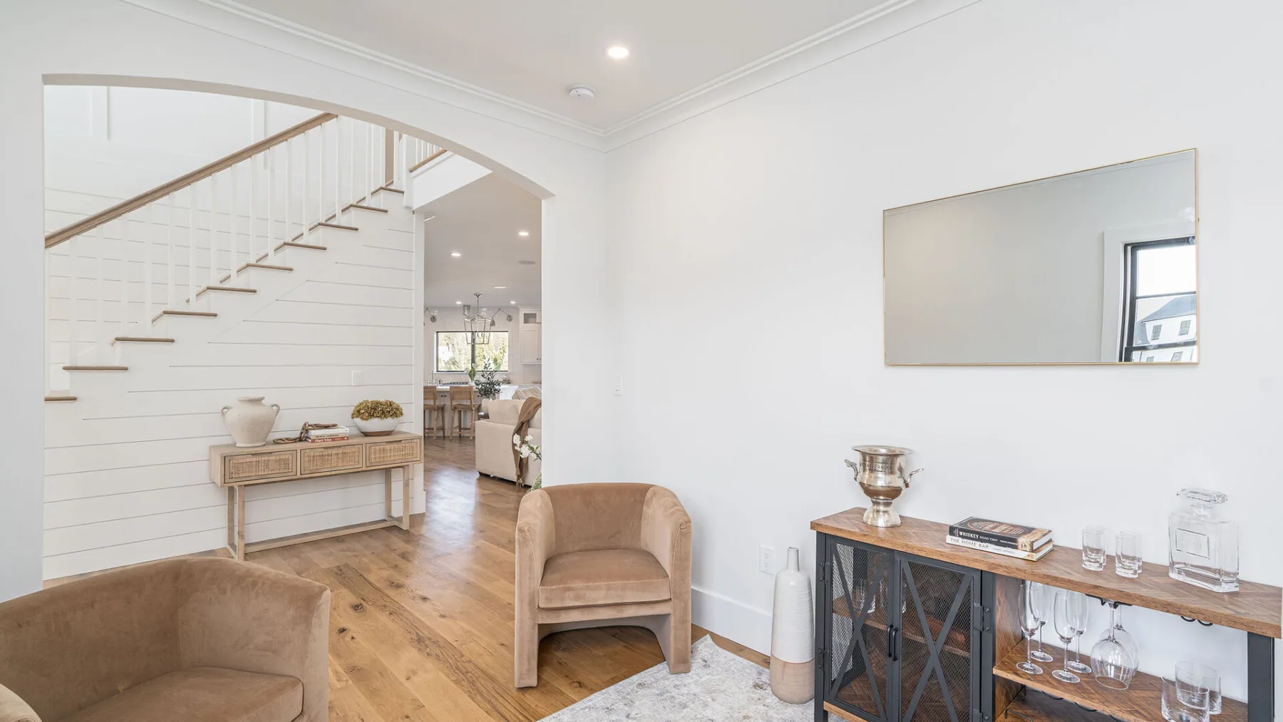 A bright living area with a staircase and a console table beneath a wall mirror.