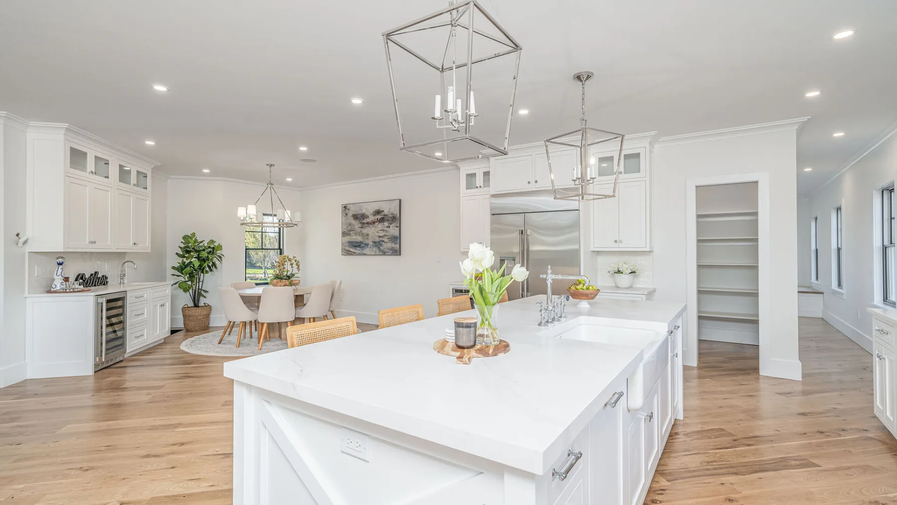 A bright kitchen and dining area with a large island and light wood flooring.