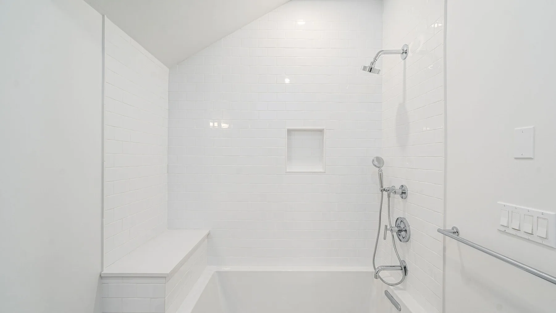 A bright tiled bathroom with a bathtub and wall-mounted shower.