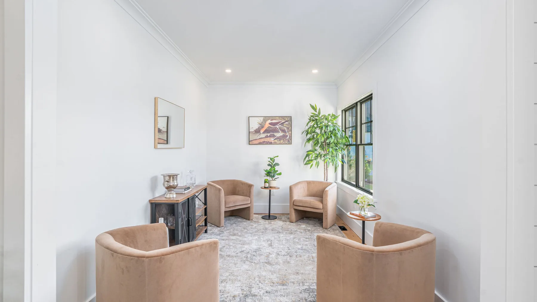 A bright sitting area with upholstered seating, a rug, and a large window.