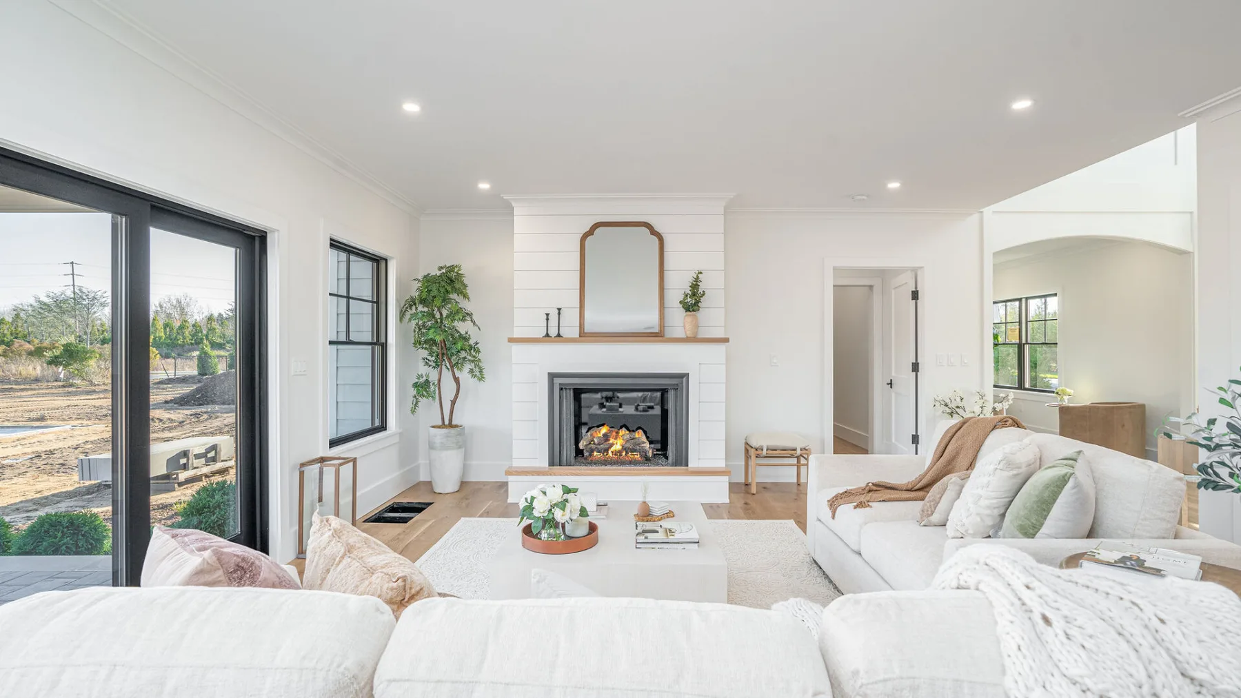 A bright living room with a fireplace and seating beside large windows.