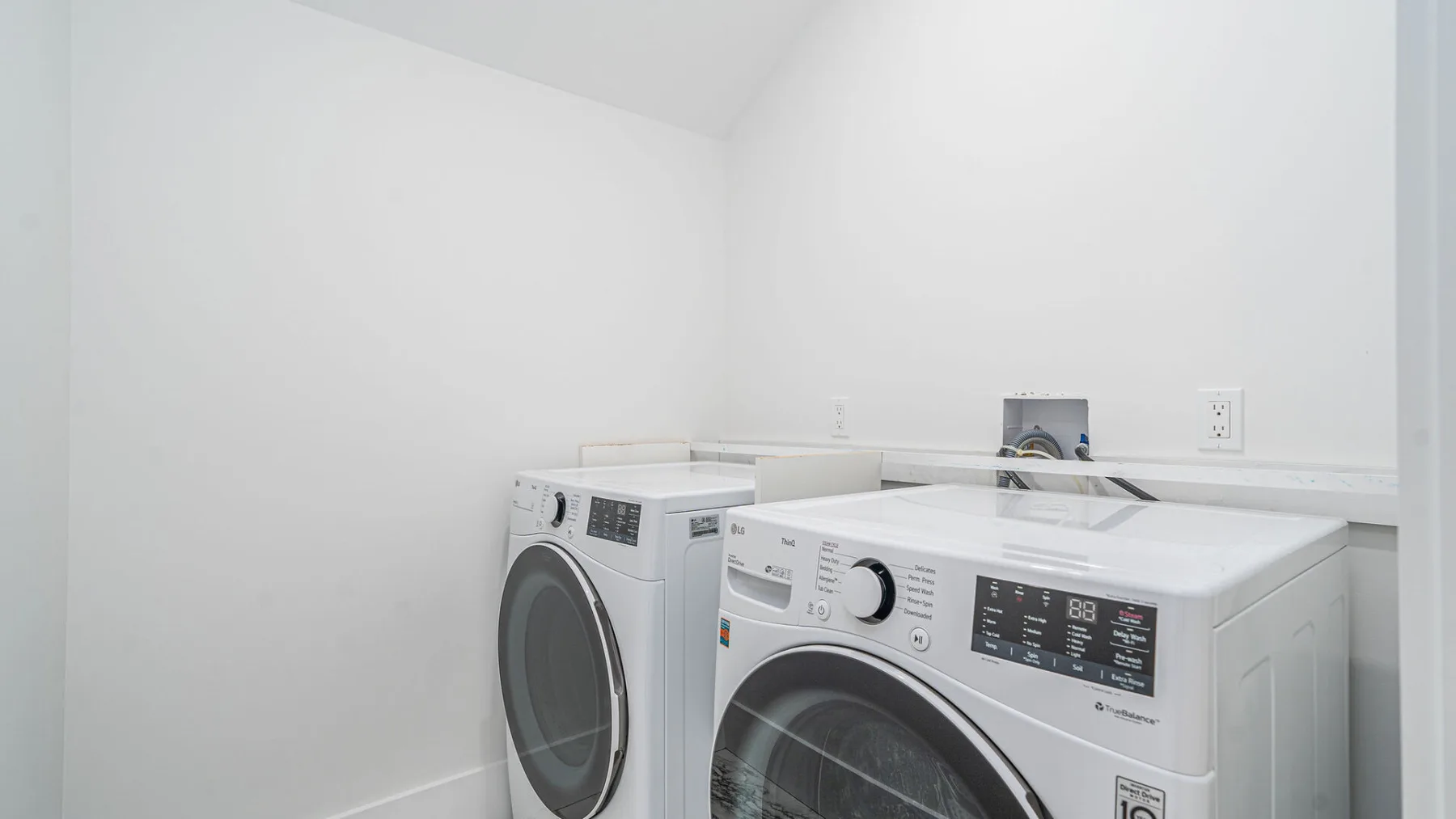 Laundry room with a washer and dryer against a white wall.