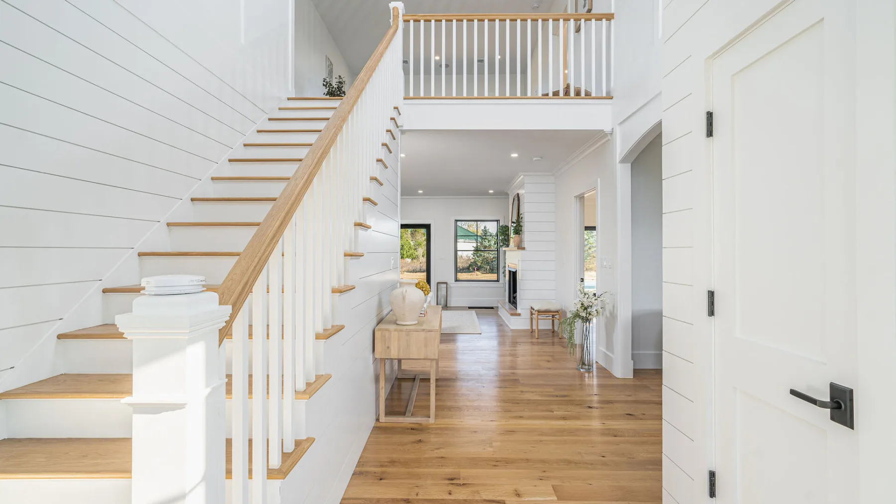 A bright entry hall with a wooden staircase and an open living area.