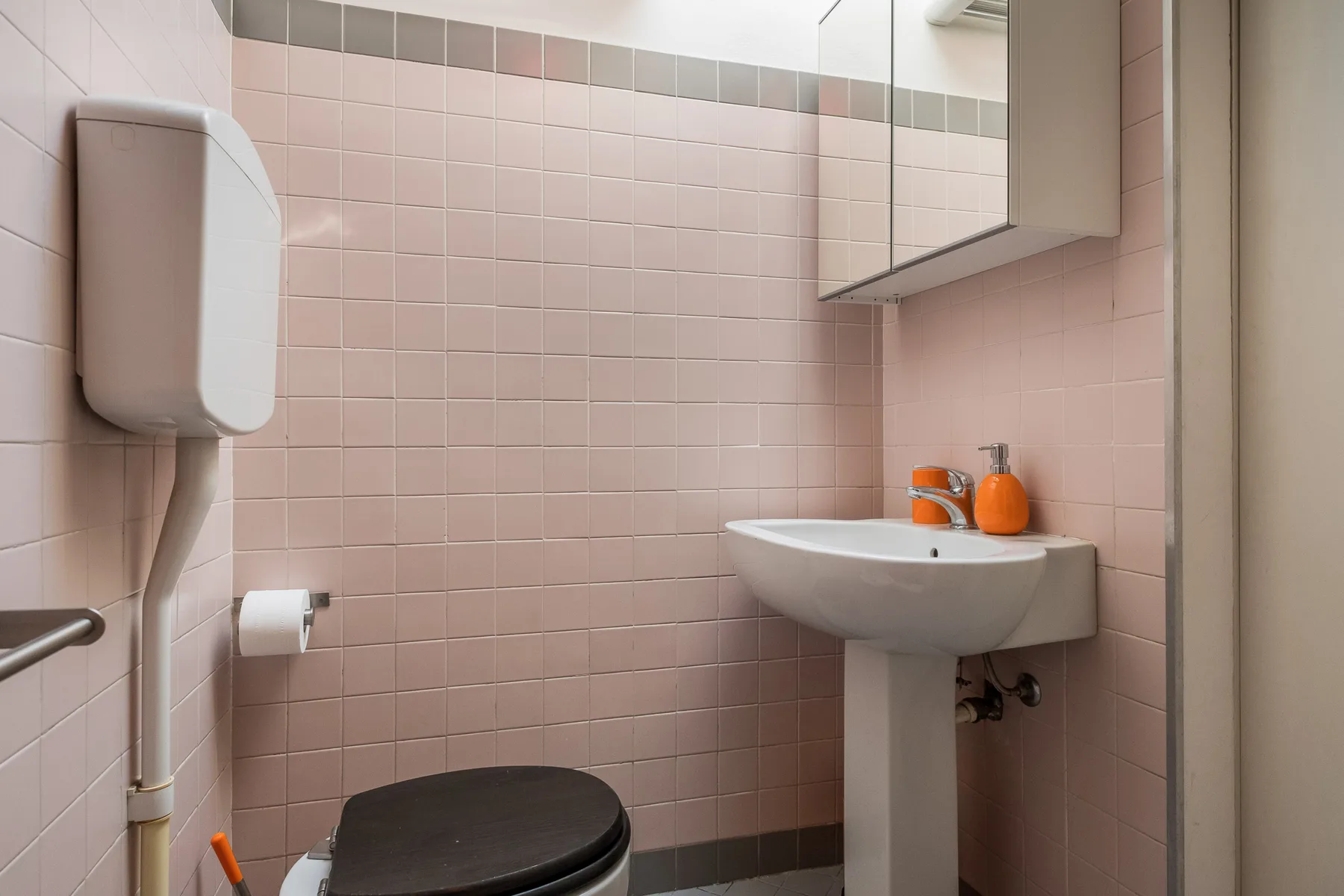 Un baño alicatado con un lavabo de pared y un inodoro.