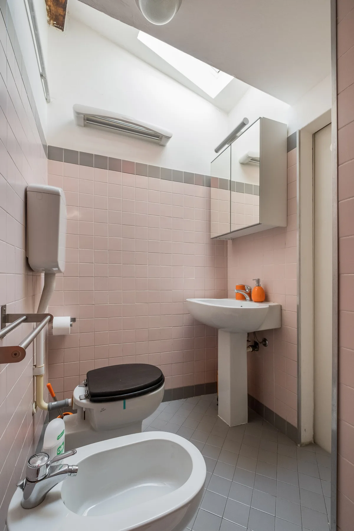 Un baño con azulejos, inodoro, bidé y lavabo de pared.