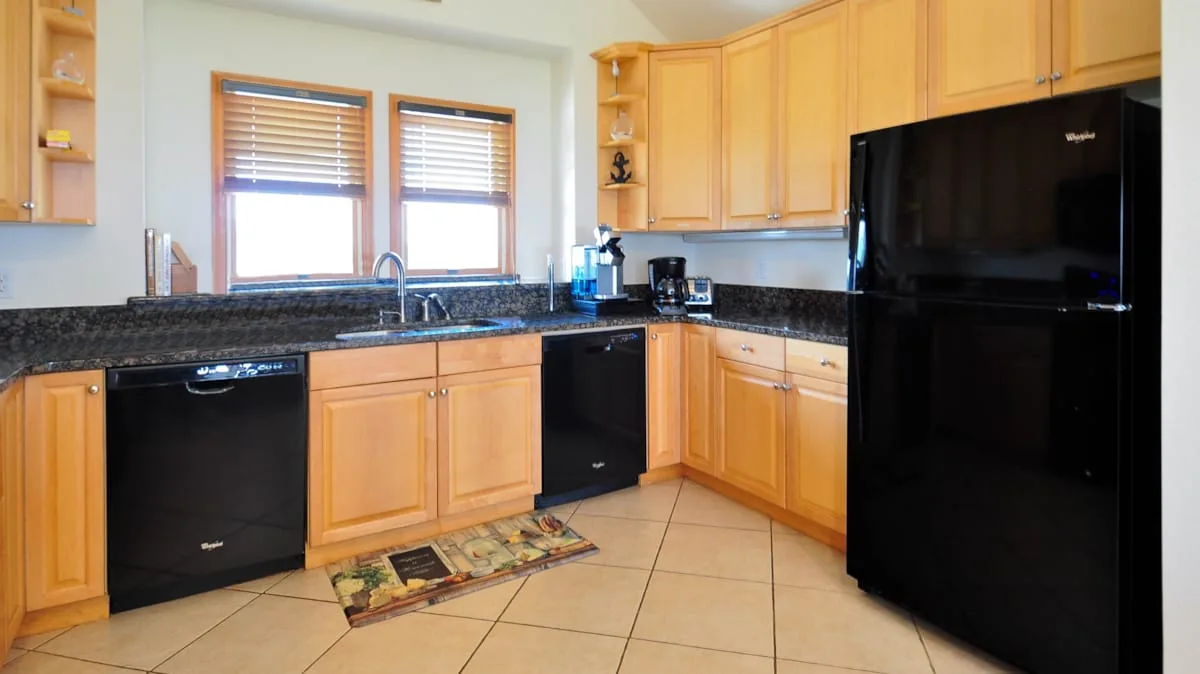 Una cocina con gabinetes de madera, fregadero y electrodomésticos negros.